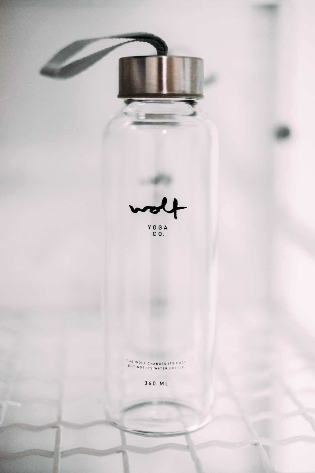 Glass water bottle with the wolf mark and the line: the wolf changes its coat but not its water bottle — 360 ml