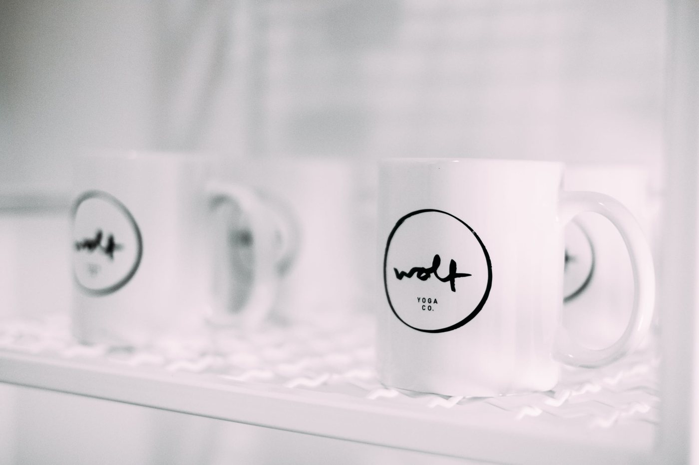 White mugs with the wolf mark inside a hand-drawn circle
