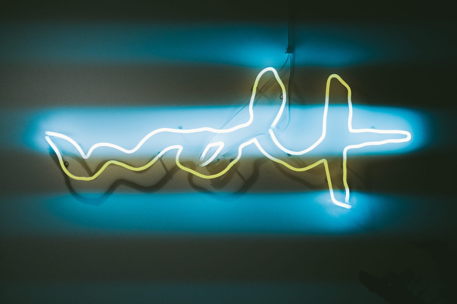 The neon sign at dusk — the wolf stroke in warm yellow inside a cold blue halo