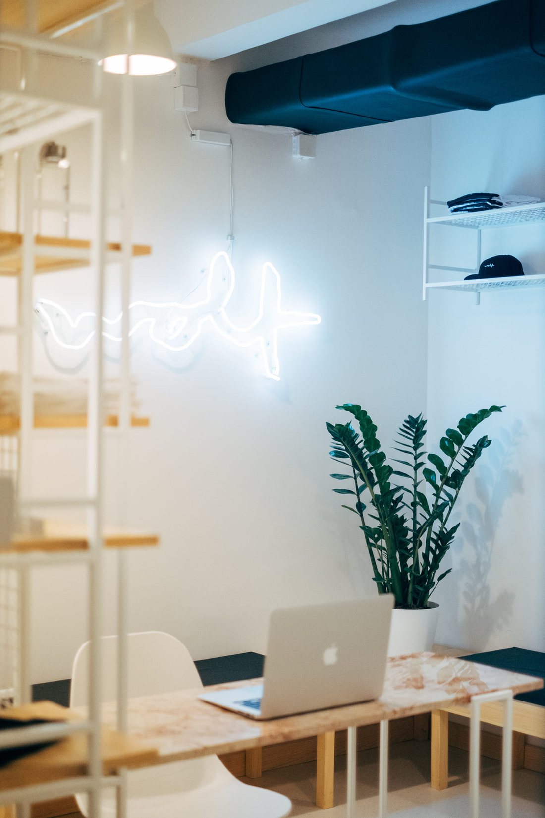 The reception corner — neon, plant, laptop on the marble desk
