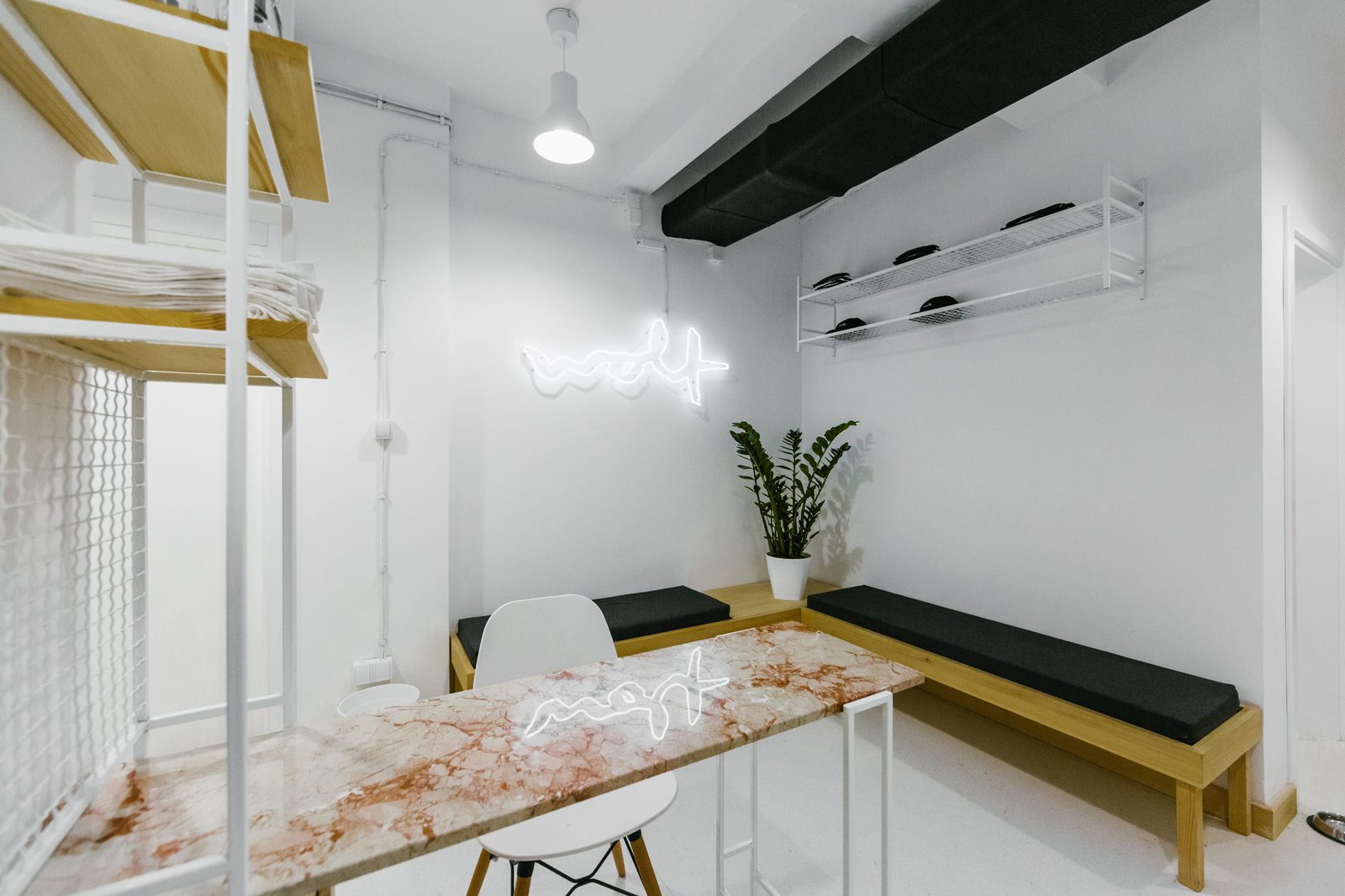 Wolf Yoga Co. reception — white walls, wood benches with black cushions, the neon on the wall, marble counter
